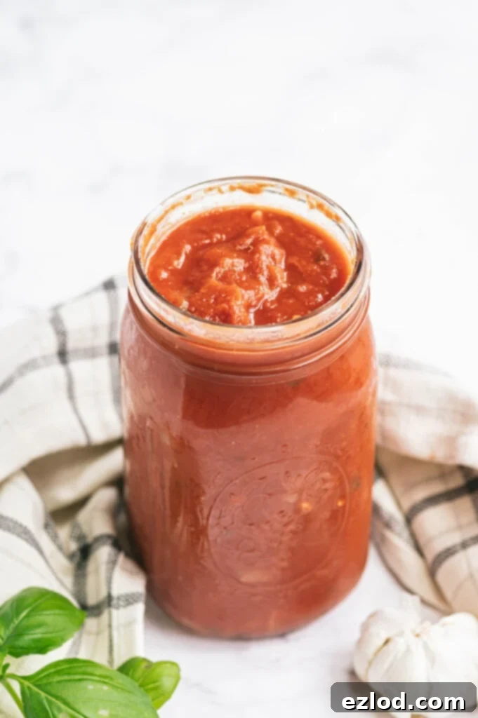 Rich 21 Day Fix Homemade Tomato Sauce in a pot, simmering gently with fresh basil garnish.