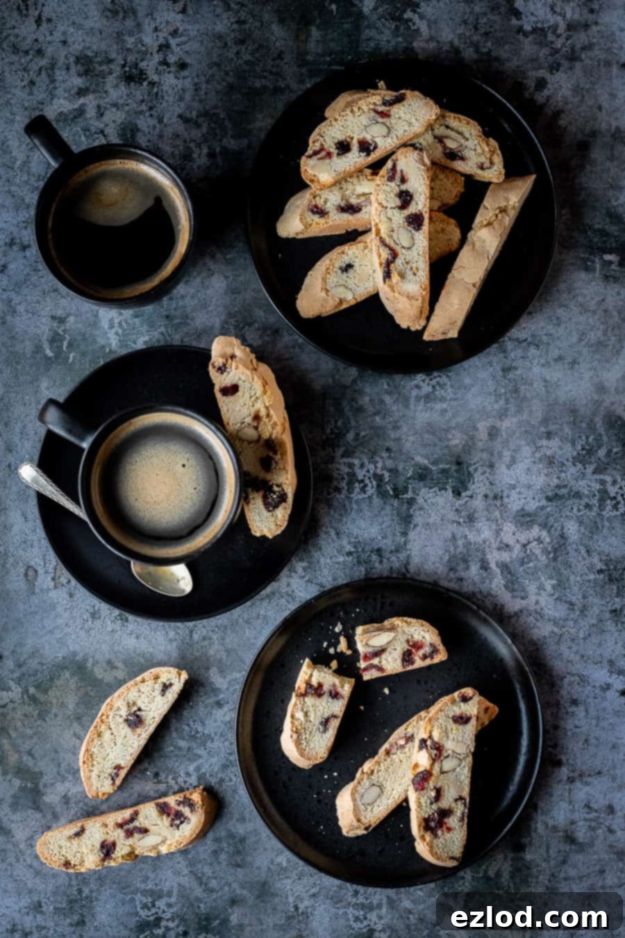 Vegan biscotti on two black plates with two black cups of coffee.