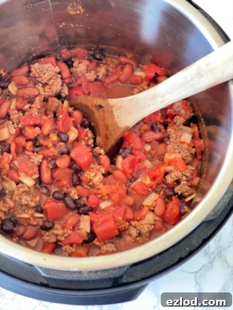 Instant Pot filled with perfectly cooked 5-ingredient chili, served with a wooden spoon on the side, showcasing its rich texture.