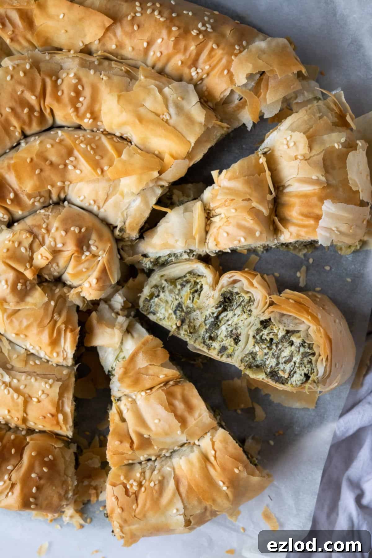 Close-up of multiple slices of vegan spanakopita, showing the layers of pastry and vibrant green filling.