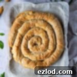 Vegan spanakopita spiral on a baking sheet with fresh herbs.