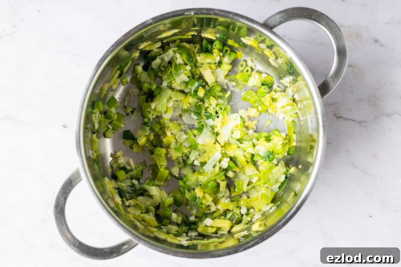 Step-by-step image of sliced leeks cooking in a pan with olive oil.