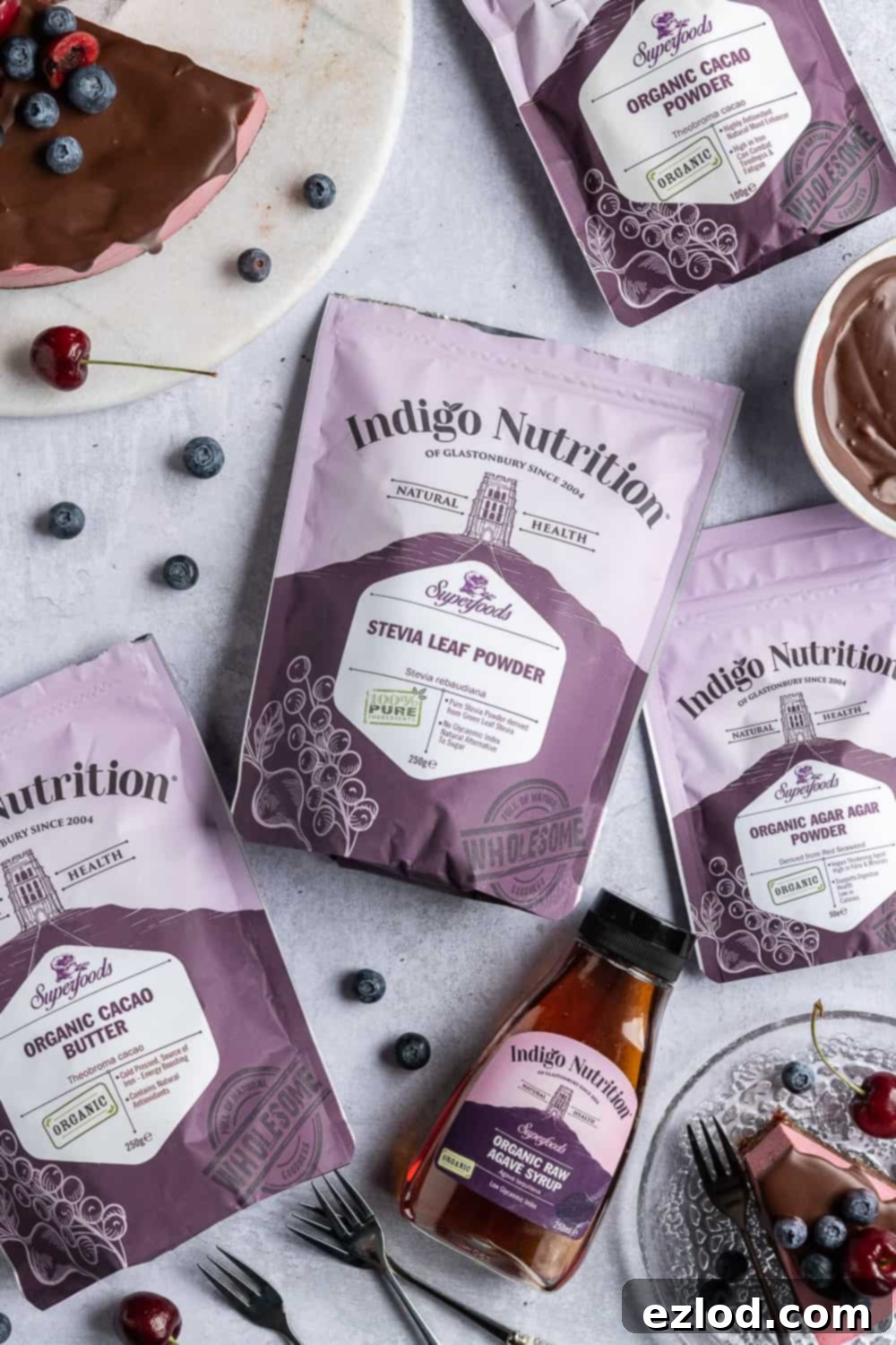 Packets of Indigo Herbs products including stevia leaf powder, organic cacao butter, organic agar agar powder, agave nectar, and cacao powder, neatly arranged for photography.