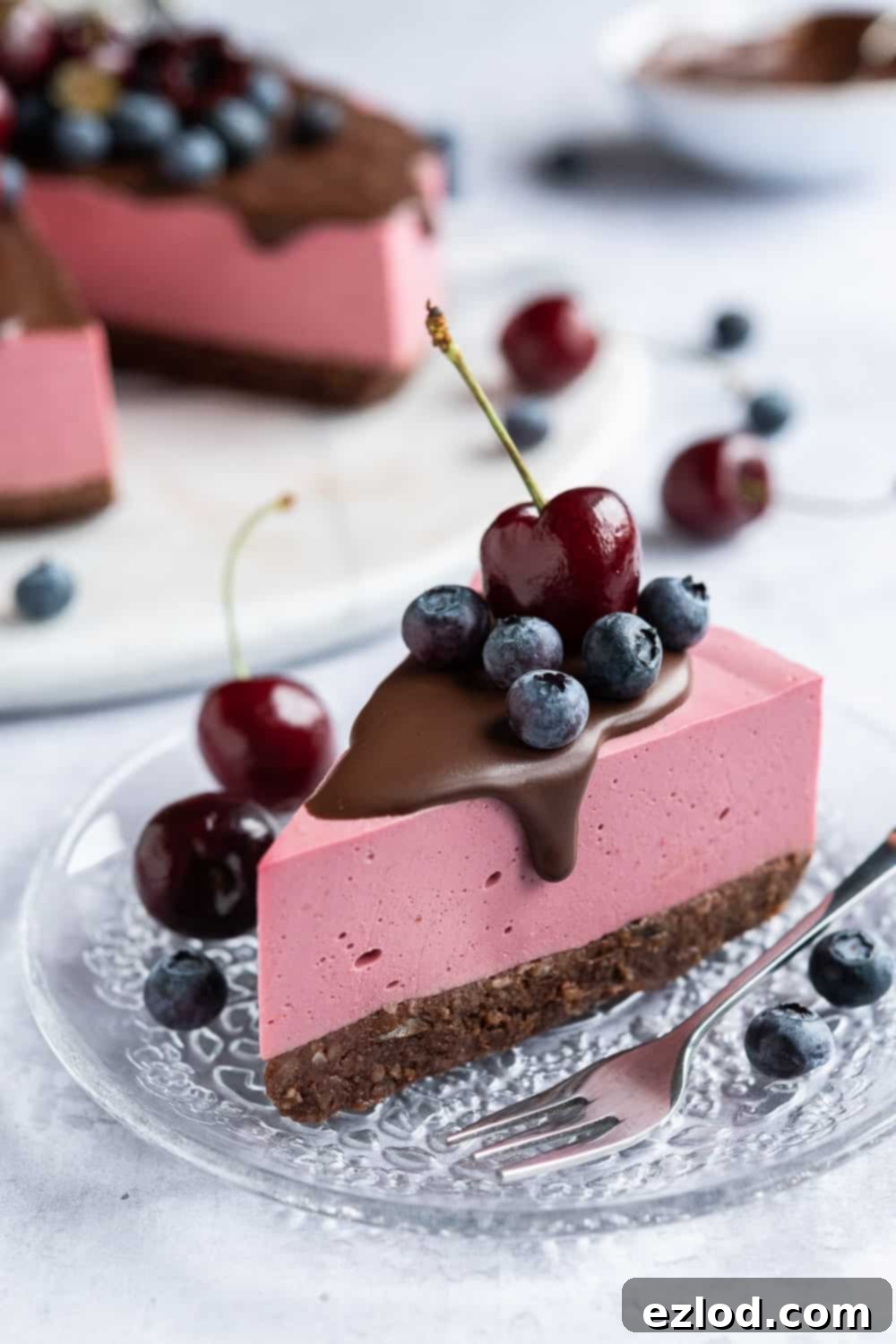 A perfectly portioned slice of no-bake vegan chocolate cherry cheesecake on a pristine glass plate, showcasing its layers and smooth texture.
