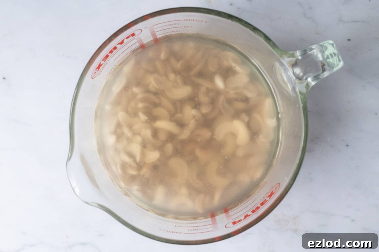 Step 1: Raw cashews soaking in water in a glass bowl, preparing them for the creamy no-bake vegan chocolate cherry cheesecake filling.