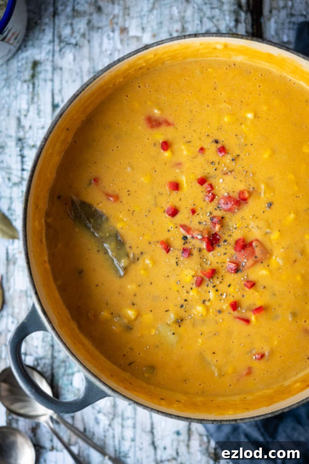 Close up of a pan of corn chowder sprinkled with chopped red chili.