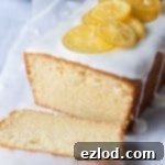 Loaf of cake with one slice on white baking parchment.