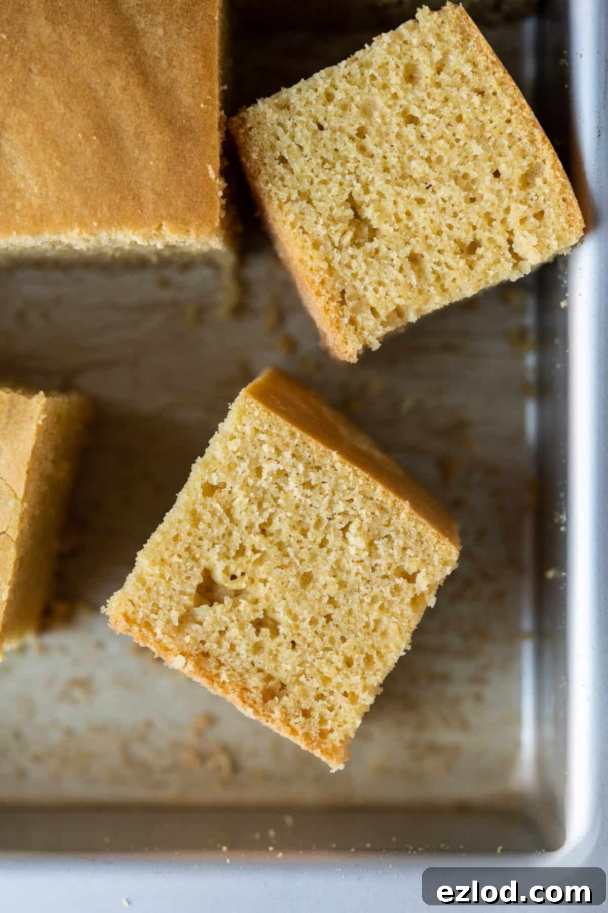 A close-up of a single square of golden-brown vegan cornbread, showing its tender crumb and inviting texture.