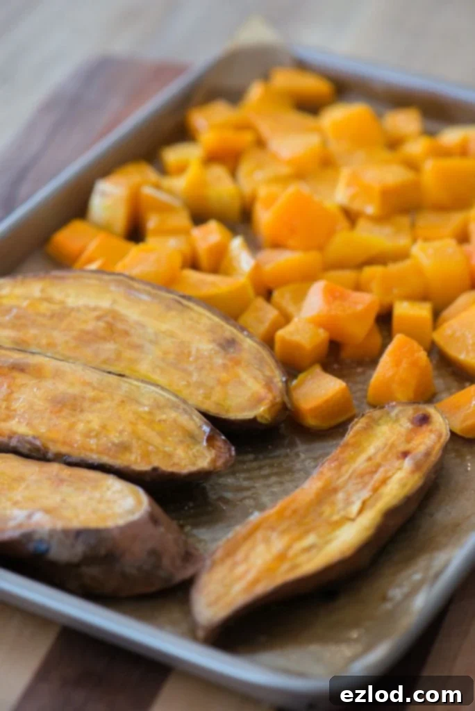 A sheet pan with sweet potatoes and butternut squash cubes 