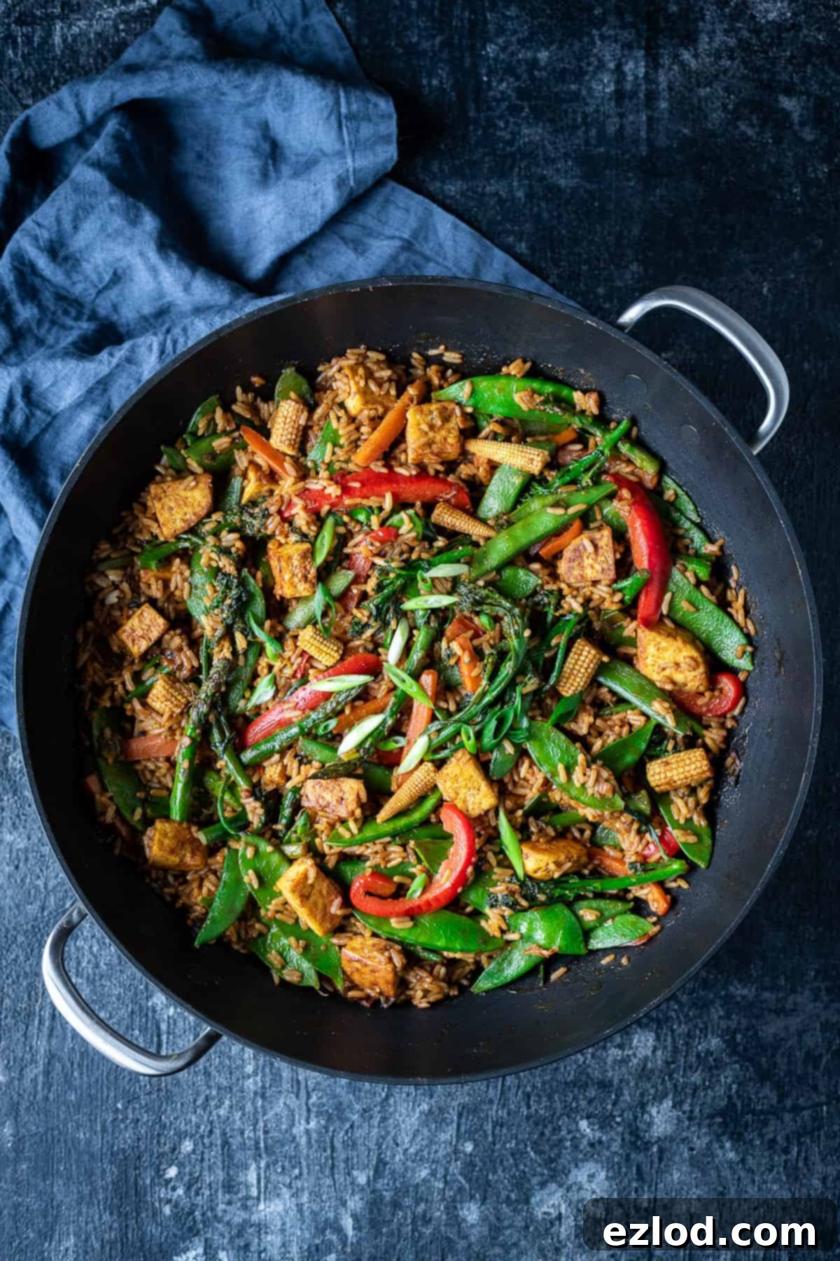 vegetable peanut fried rice in a black wok on a black background with a grey cloth.