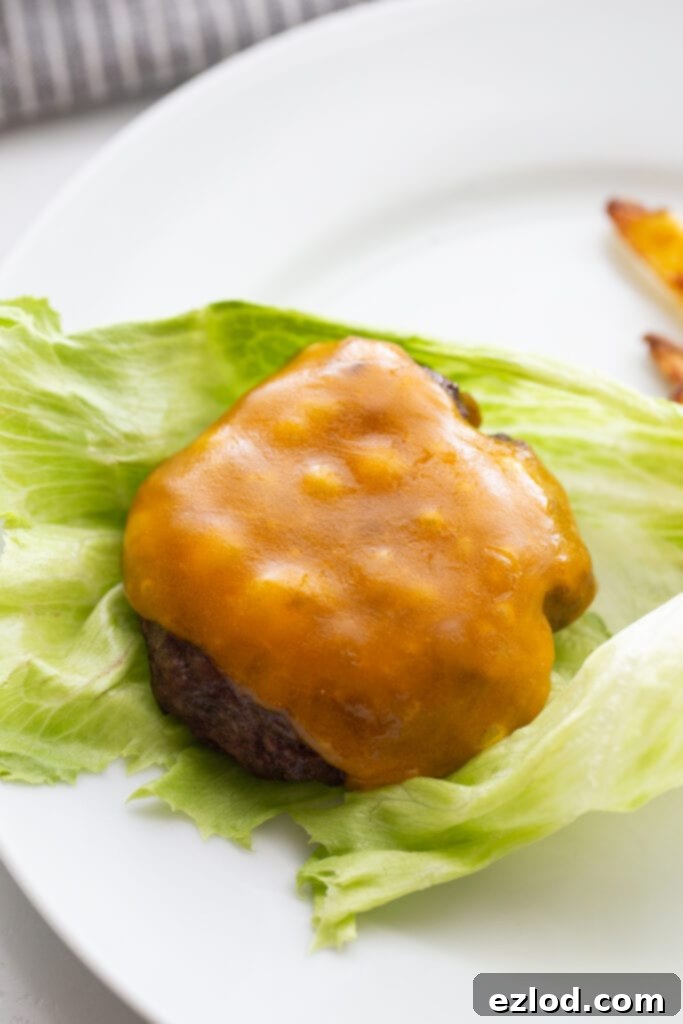 Overhead photo of the best burger topped with cheddar cheese and resting on a large lettuce leaf. The lettuce will wrap the burger for a bunless option.