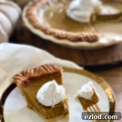A beautiful, golden-brown Healthy Pumpkin Pie, topped with white coconut cream, is shown in a white pie plate.