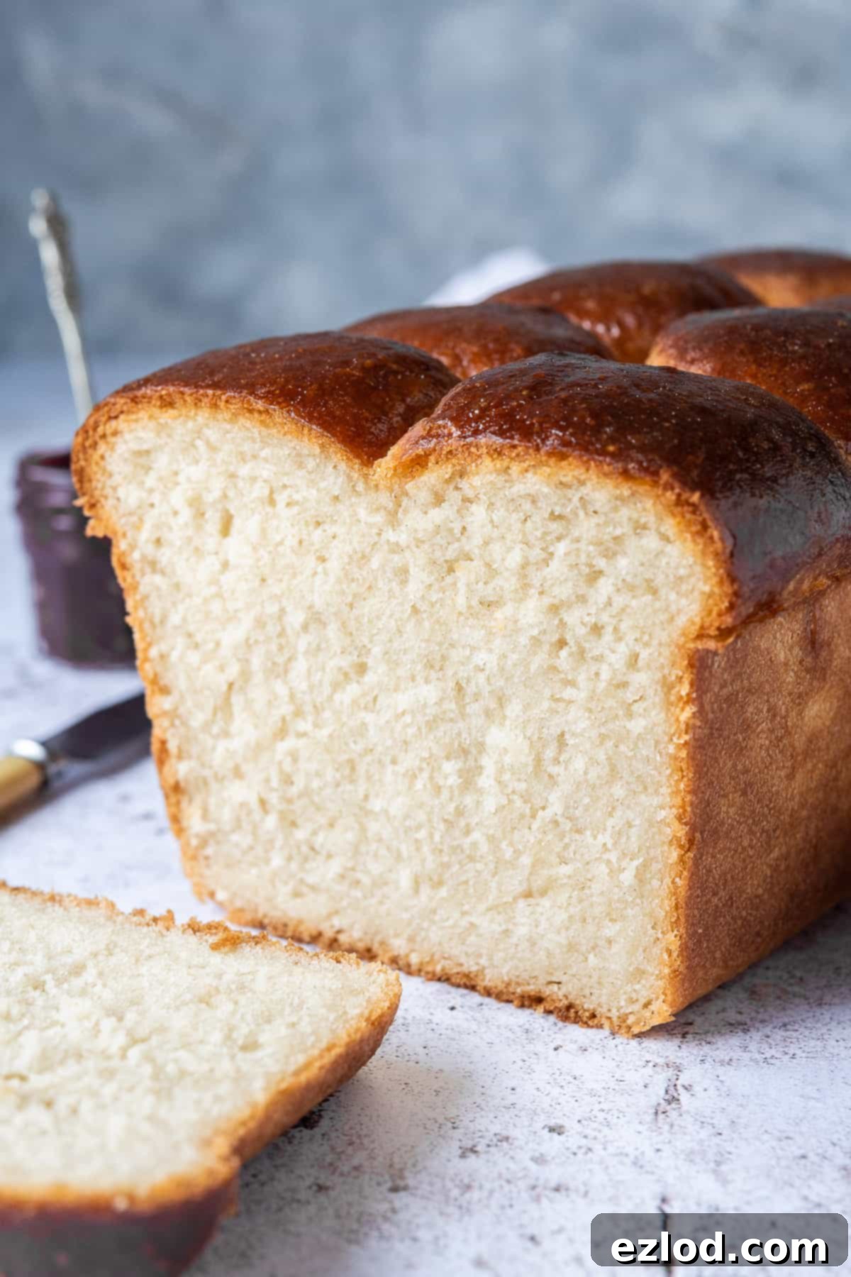 Side shot of a loaf of vegan brioche with a slice cut off.