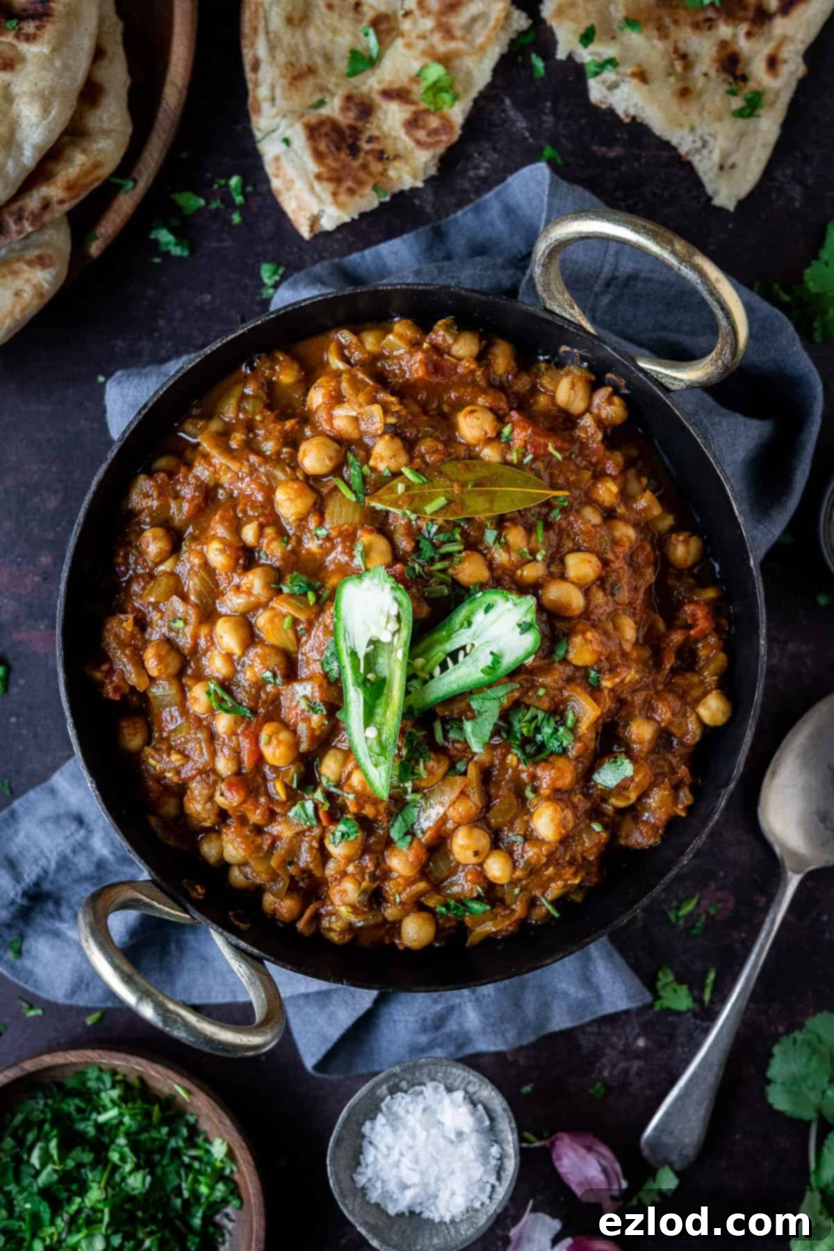 chickpea curry in a black bowl on a dark background with a grey cloth.