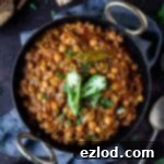 chickpea curry in a black bowl on a dark background with a grey cloth.