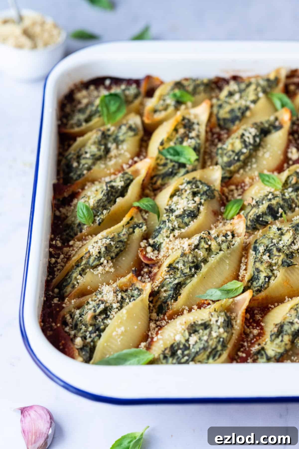 Overhead view of vegan stuffed pasta shells baked in a white ceramic dish, ready to be served.