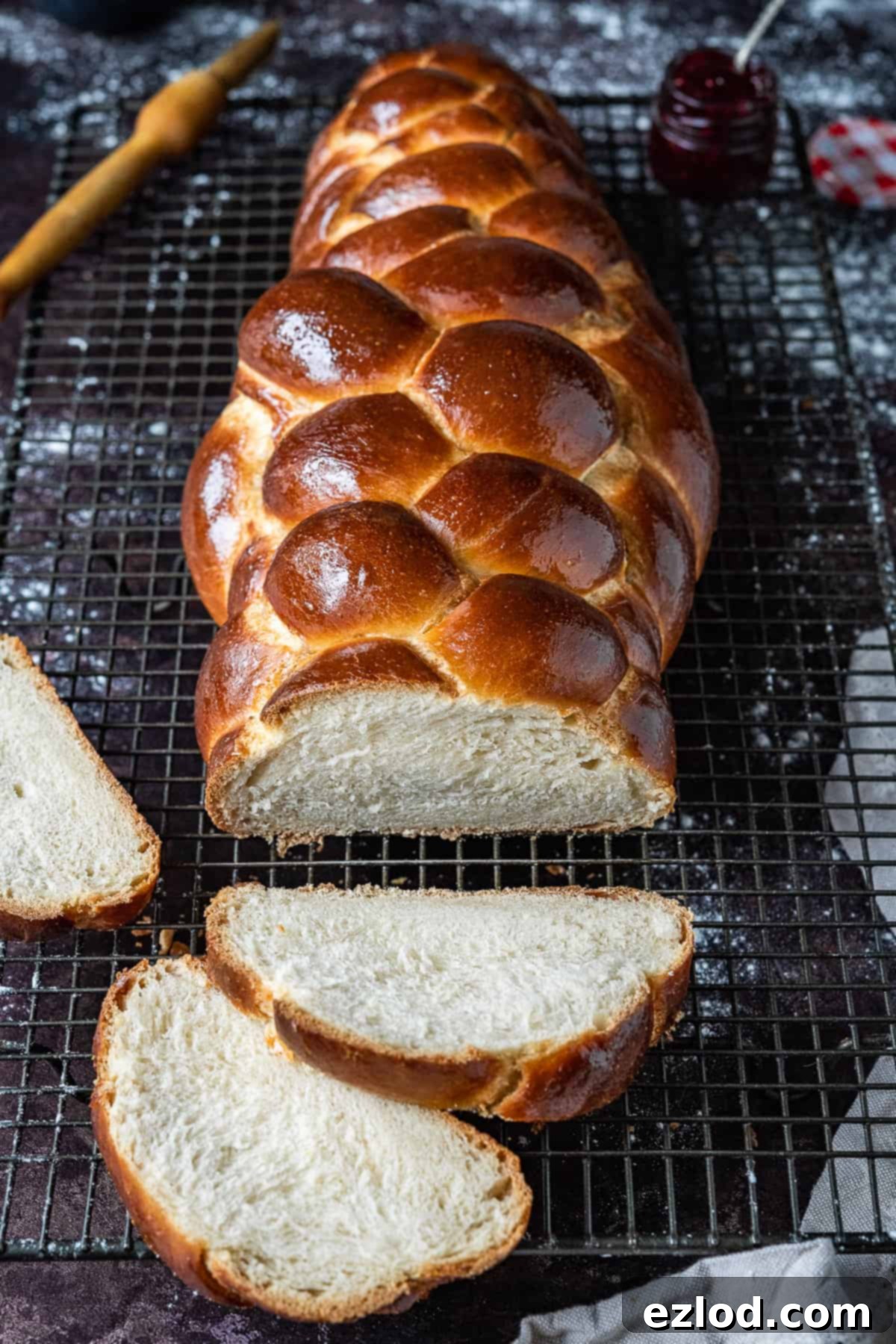 A golden-brown loaf of freshly baked vegan water challah, beautifully braided and sliced, presented on a simple wire rack, highlighting its delightful texture.
