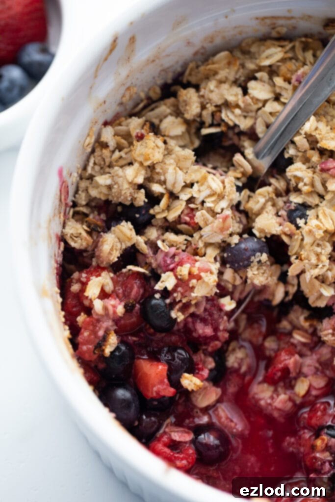 A large casserole dish filled with a baked mixed berry crisp, beautifully topped with a golden-brown layer of gluten-free oats. This delightful dessert was cooked to perfection in the Instant Pot.