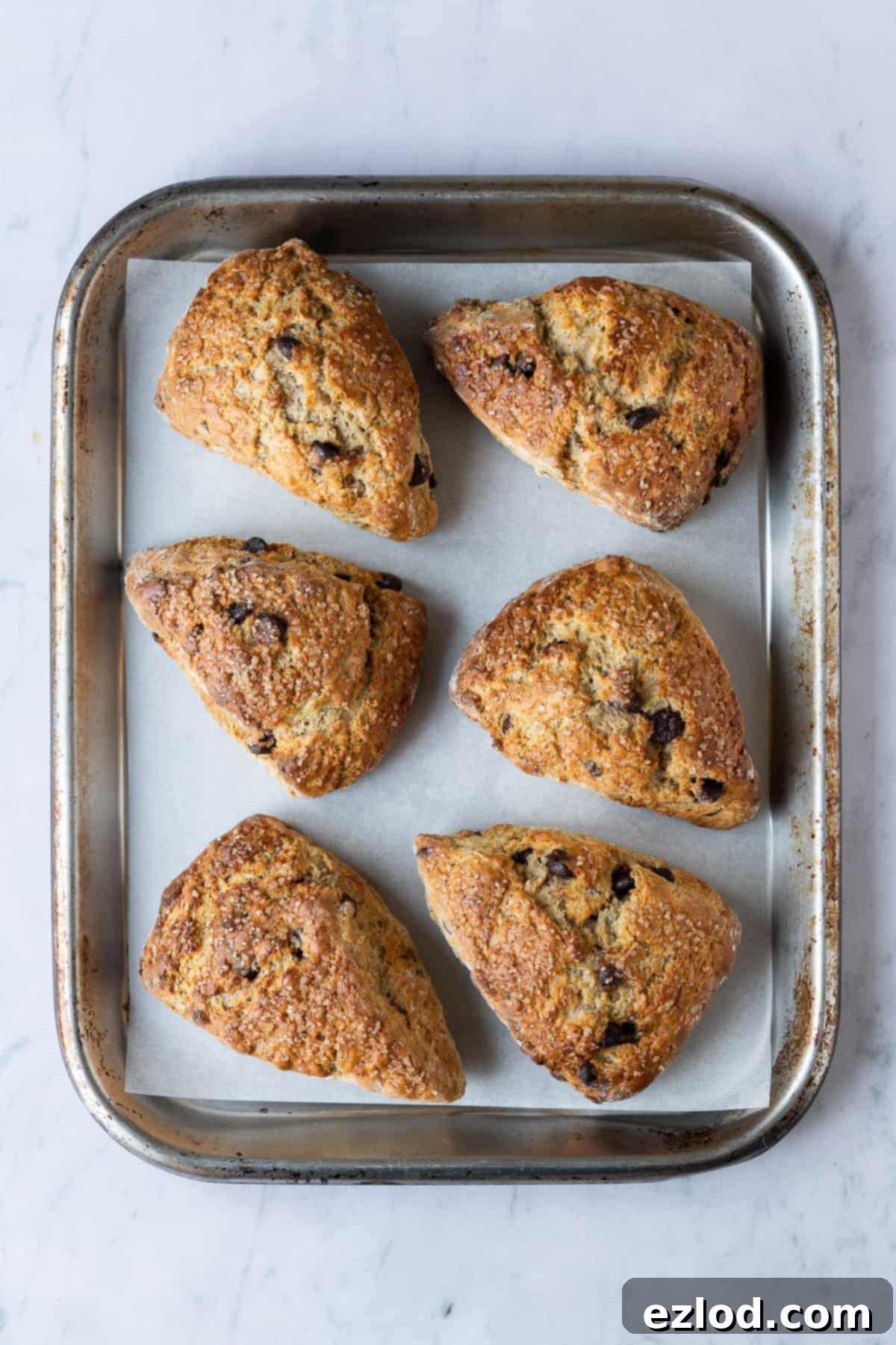 Vegan banana scones arranged on a metal baking tray against a stylish marble background, highlighting their golden crust and enticing texture.