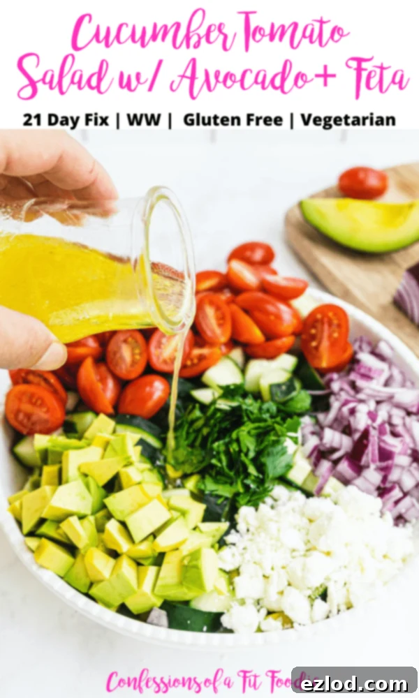 A bowl of summer salad with dressing being poured over the top with a black and pink text overlay. The text says- Cucumber Tomato Salad w/ Avocado + Feta | 21 Day Fix | WW | Gluten Free | Vegetarian | Confessions of a Fit Foodie