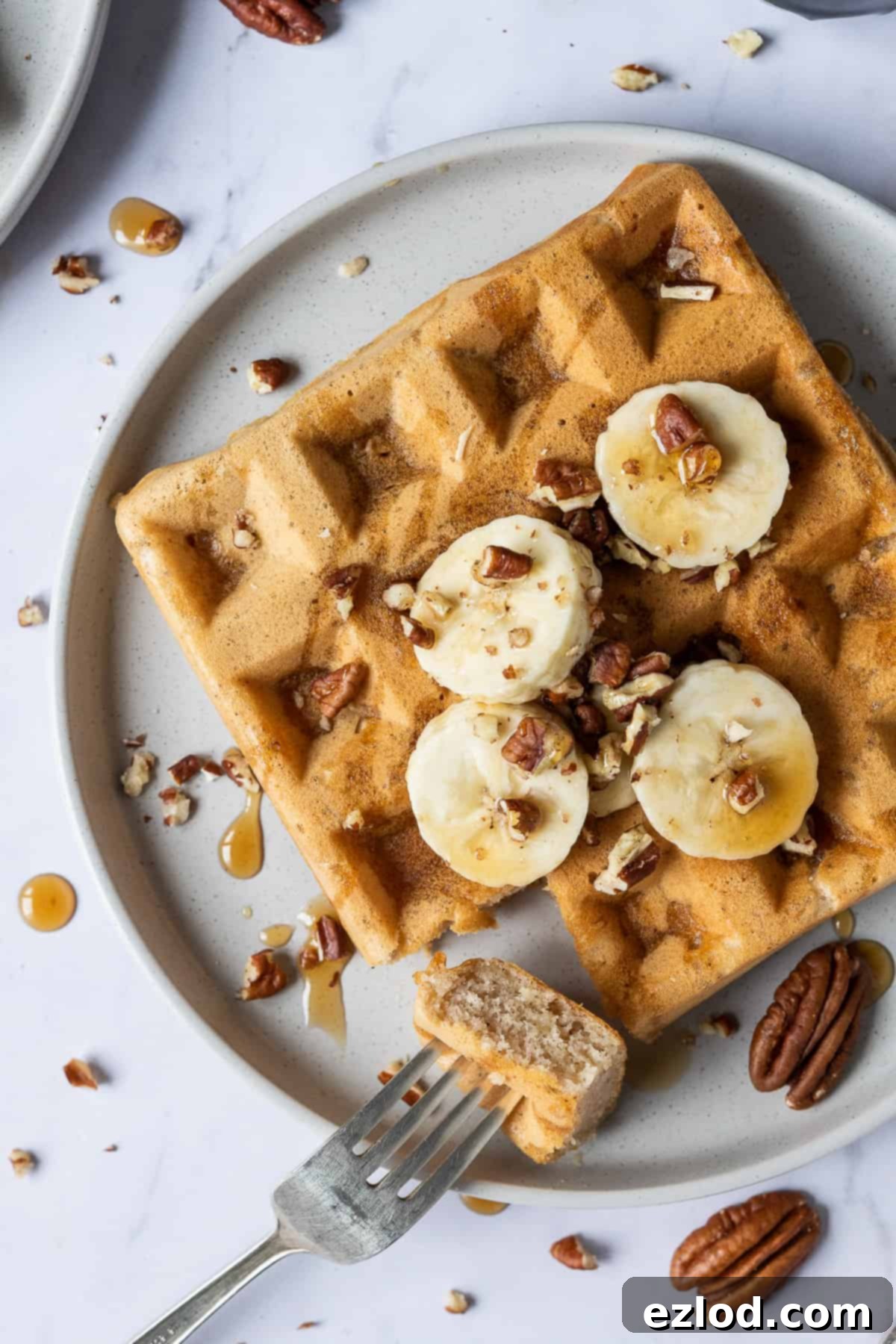 Close up of a single vegan banana waffle, showing its texture and a small bite taken out.