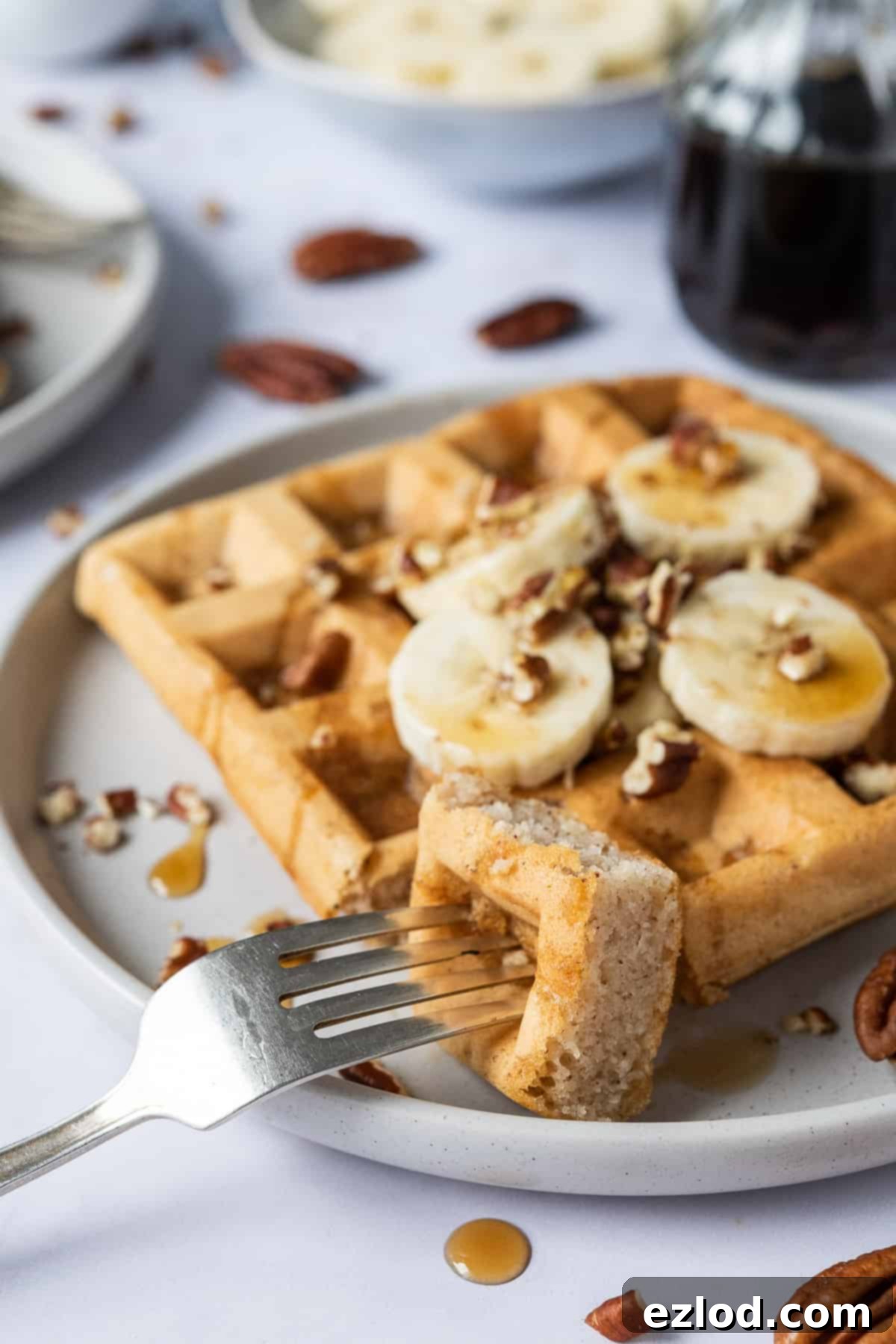 Close up of a forkful of banana waffle, showing its texture and a hint of a topping.