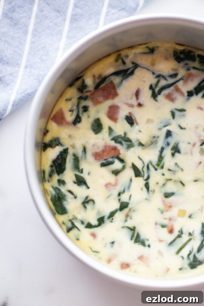 An overhead shot showcasing a perfectly baked bacon, egg, and cheese frittata in a round white casserole dish, fresh out of the Instant Pot.