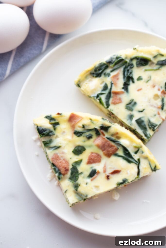 A close-up overhead photo showing two appetizing slices of bacon, cheese, and egg frittata neatly arranged on a white plate, ready to be enjoyed.