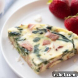 Effortless Spinach Frittata Instant Pot and Oven 9 A perfectly cooked slice of Instant Pot frittata on a white plate with fresh strawberries, illustrating its delicious appeal.