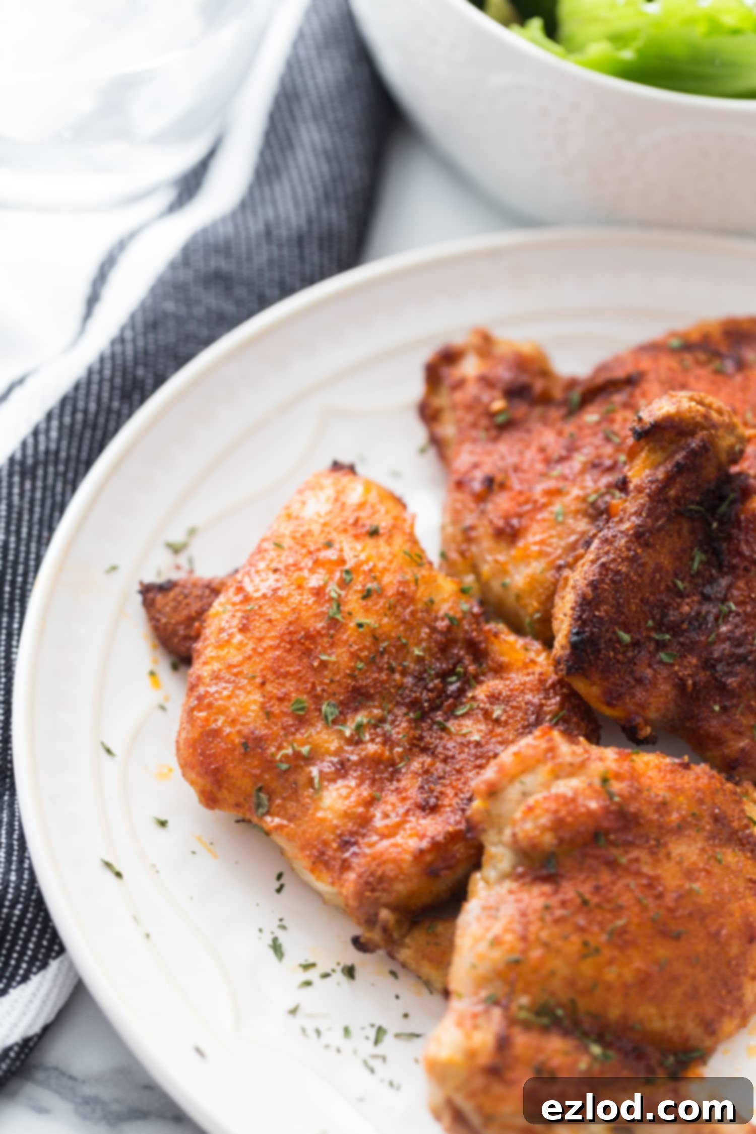 Effortless Crispy Chicken Thighs 3 Crispy air fryer chicken thighs on white serving plate