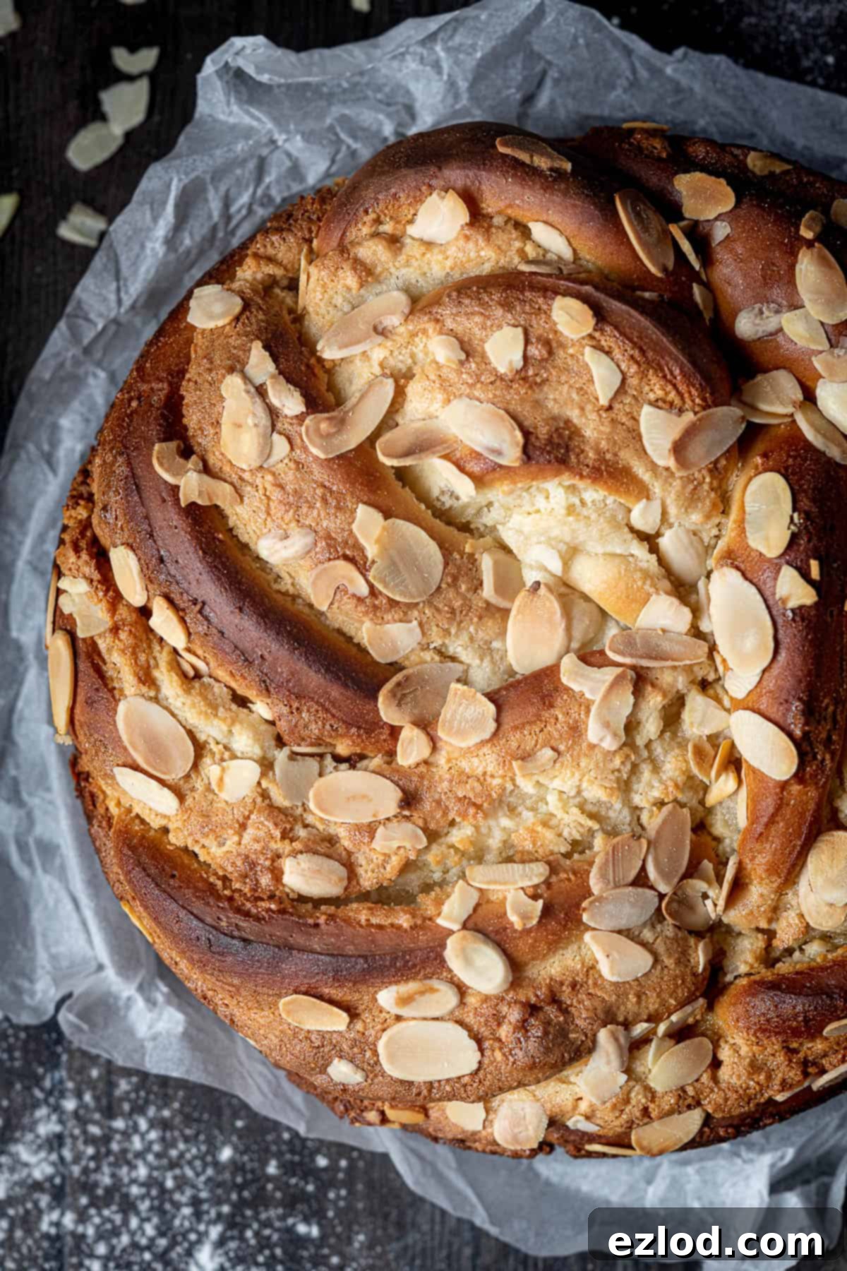 Close-up of the beautifully baked vegan almond bread twist with a golden crust and visible flaked almonds.