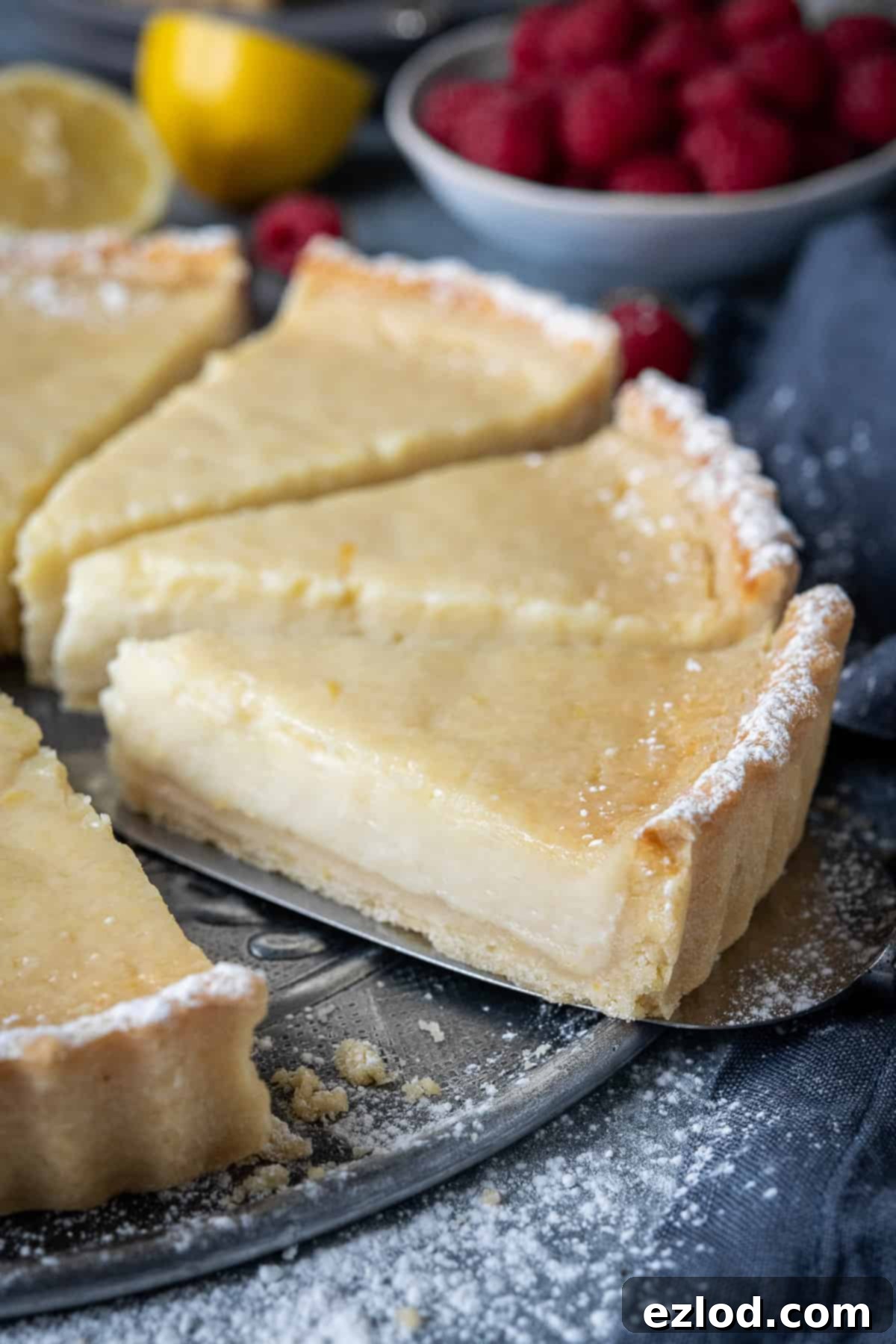 Close up image of a single slice of vegan lemon tart showing the creamy filling and crisp crust.