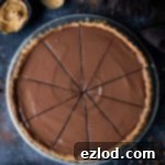 Plant-Based Peanut Butter Chocolate Tart 7 Vegan peanut butter chocolate tart cut into slices on a dark background with chocolate curls, plates, forks, a bowl of peanut butter and a brown cloth.