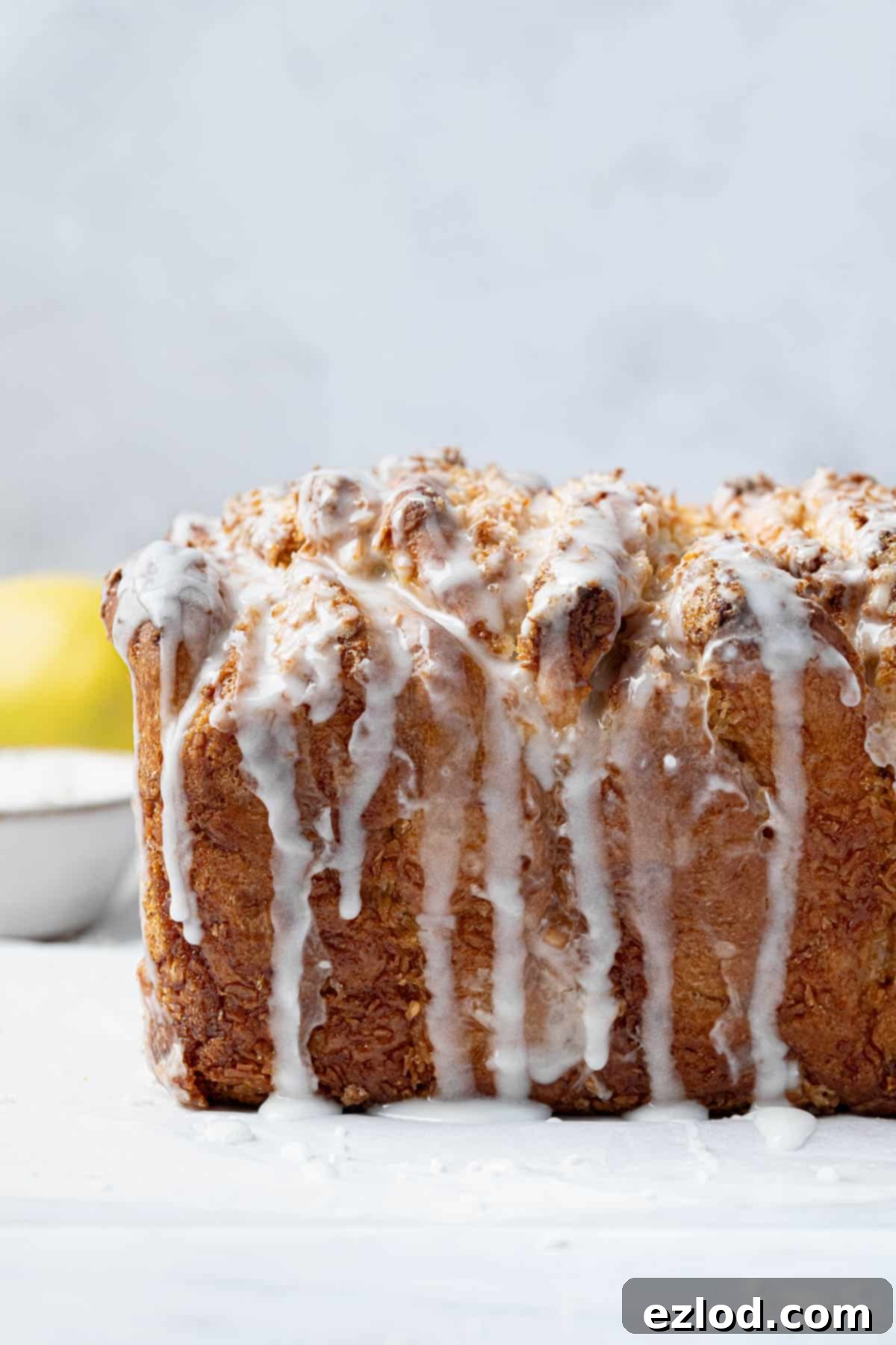 Close up shot of the side of the golden-brown lemon coconut pull-apart bread loaf, showing its soft, layered texture.
