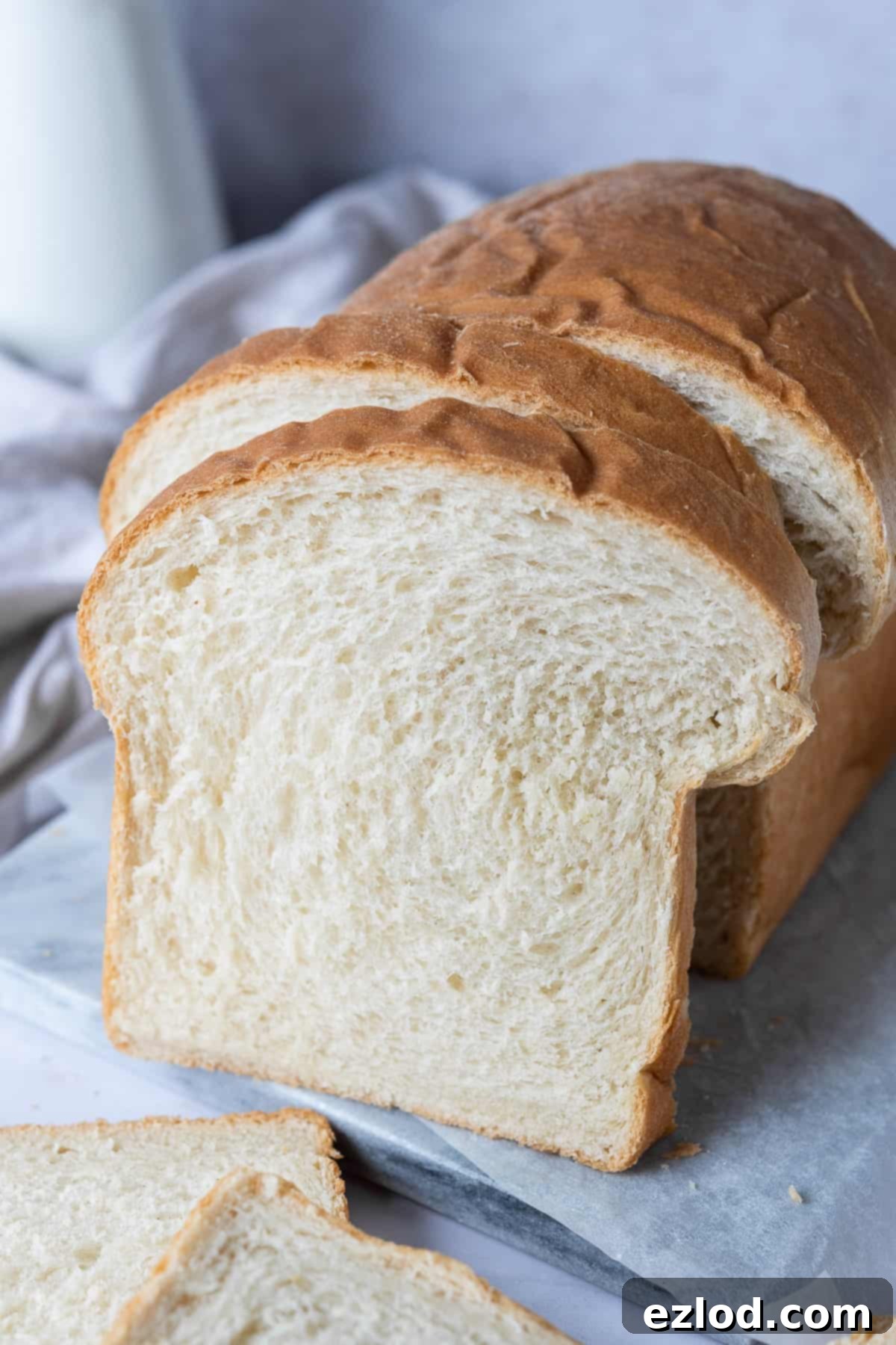 A detailed close-up of a single slice of freshly baked vegan white sandwich bread, revealing its soft, airy crumb texture.