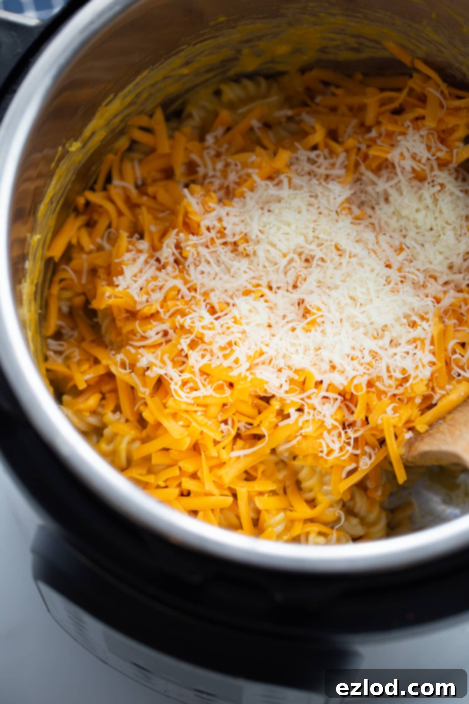 Overhead photo of shredded cheese, cooked pasta, and butternut squash ready to be mixed in the instant pot