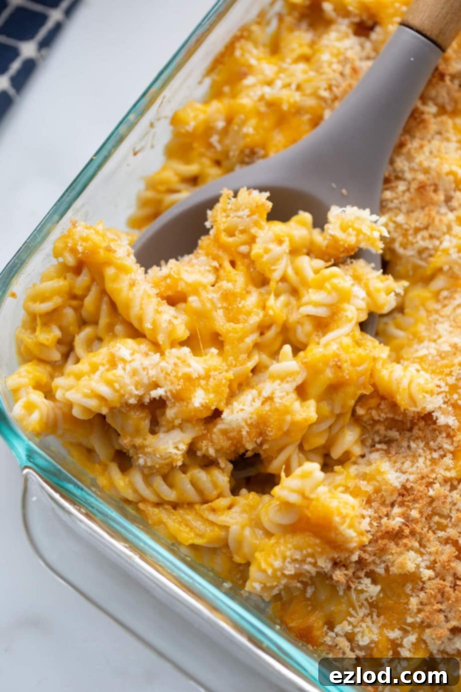Close up photo of a serving spoon scooping a portion of mac and cheese out of a baking dish.