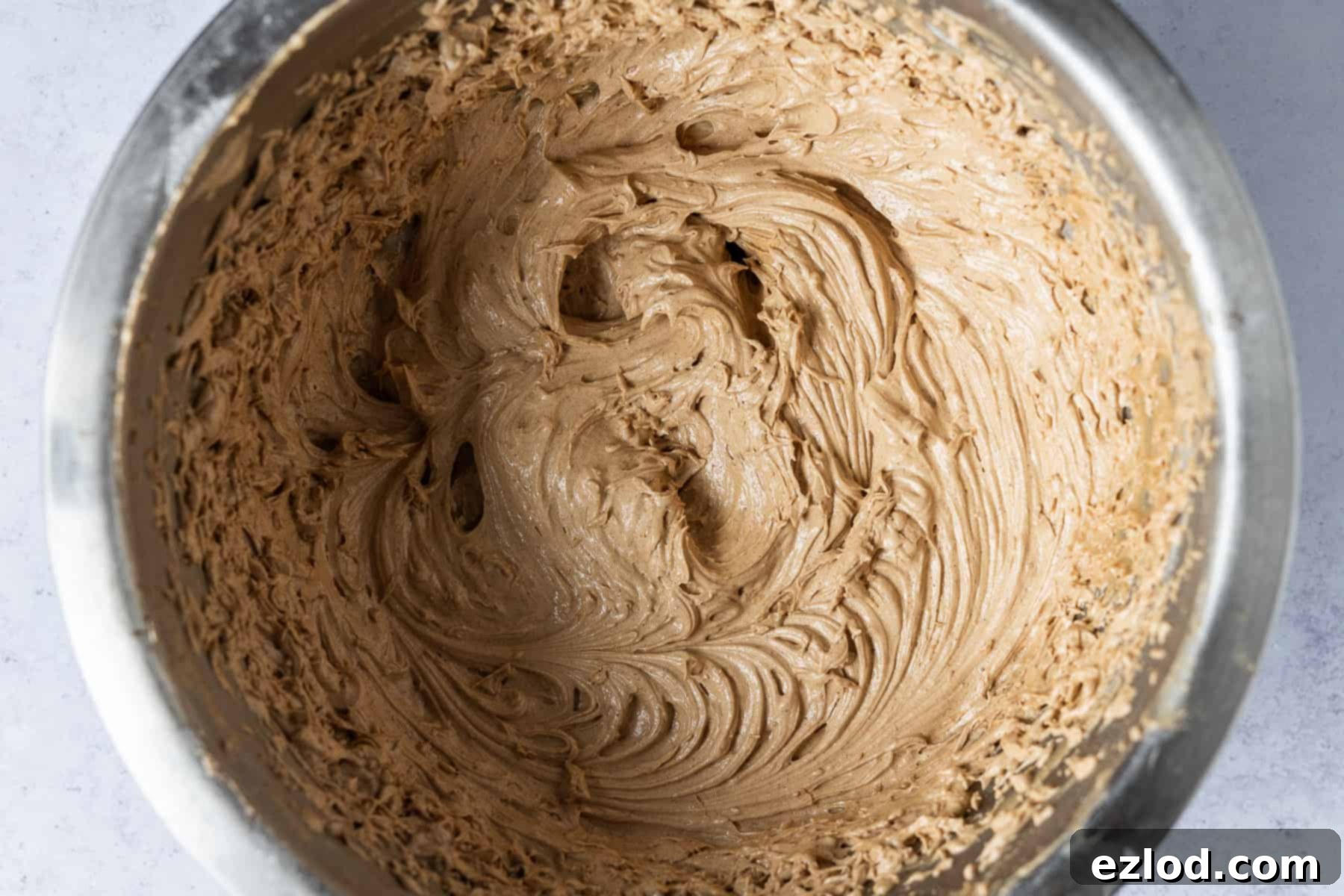 A large bowl filled with freshly made, light and airy espresso buttercream, showcasing its smooth texture and rich coffee color.