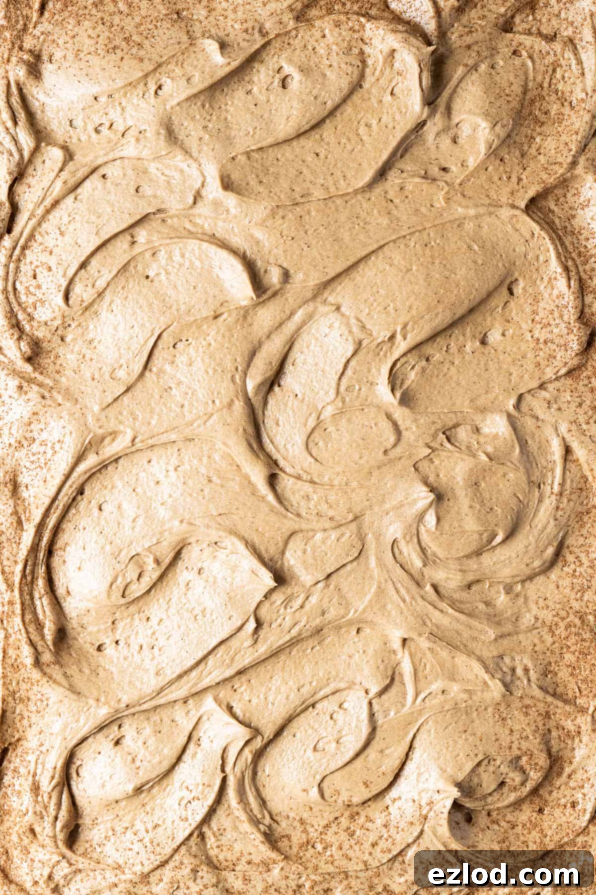 A close-up image showing the rich, swirled coffee buttercream spread generously on top of the vegan pumpkin spice latte cake, ready for serving.