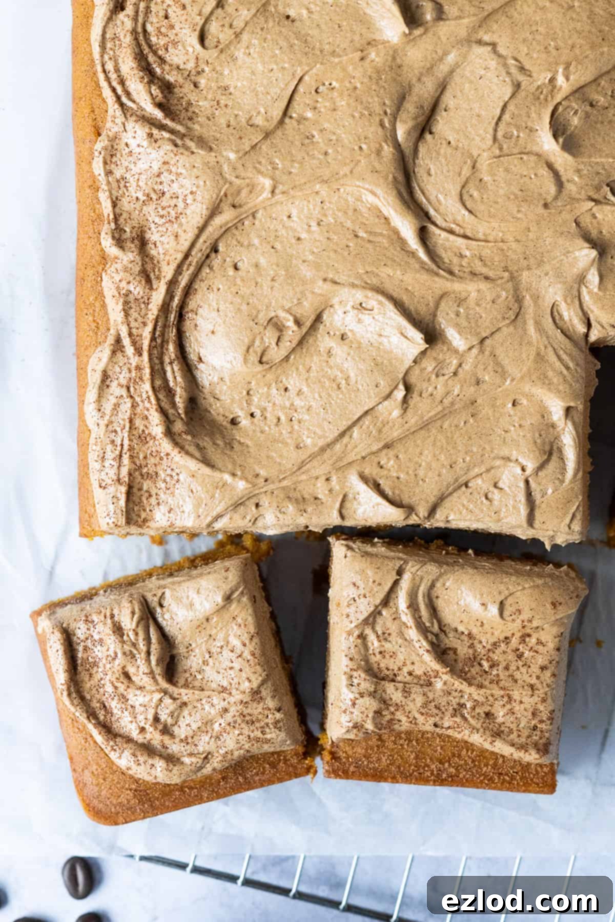 Neatly cut squares of delicious vegan pumpkin spice latte cake, showcasing the beautiful frosting and moist interior, arranged on a rustic wooden board, ready to be served.