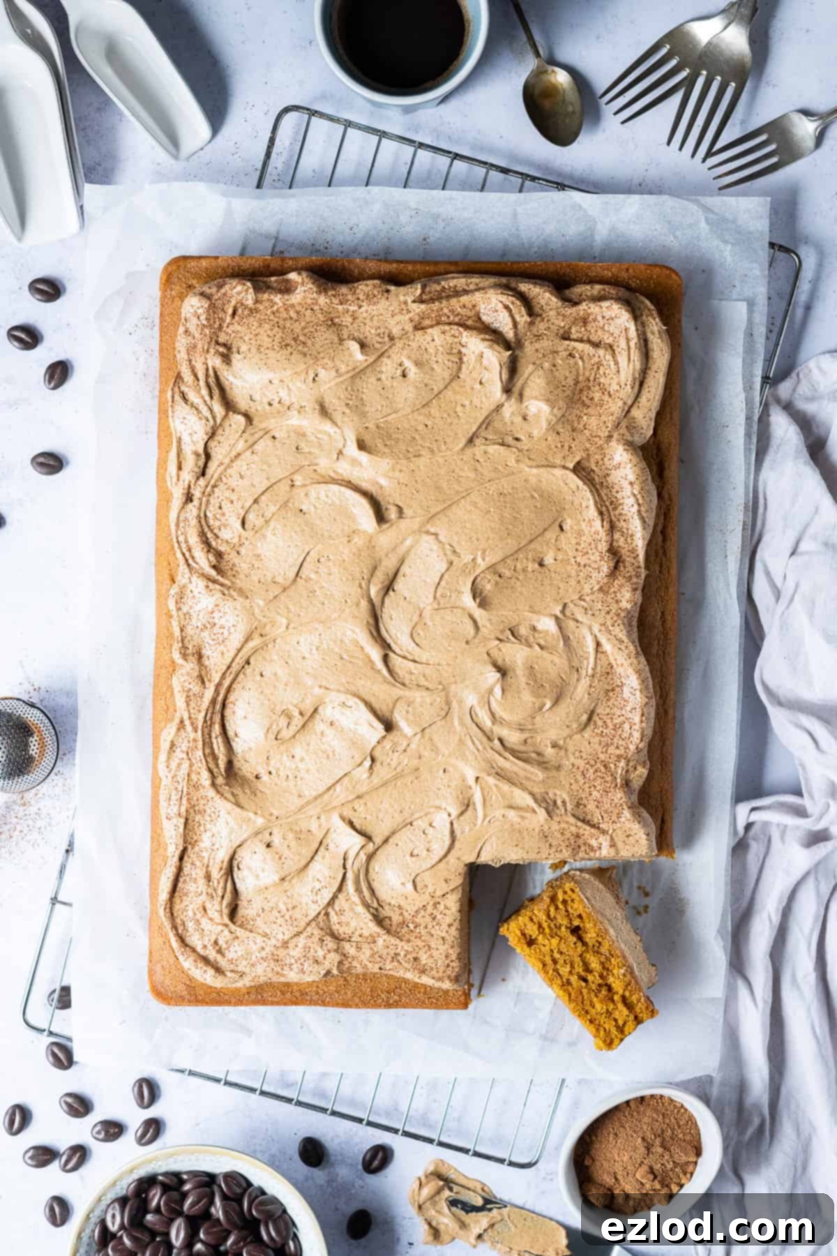 A stunning side view of the vegan pumpkin spice latte cake, with one slice elegantly turned on its side, revealing the moist cake texture and generous, creamy coffee buttercream.