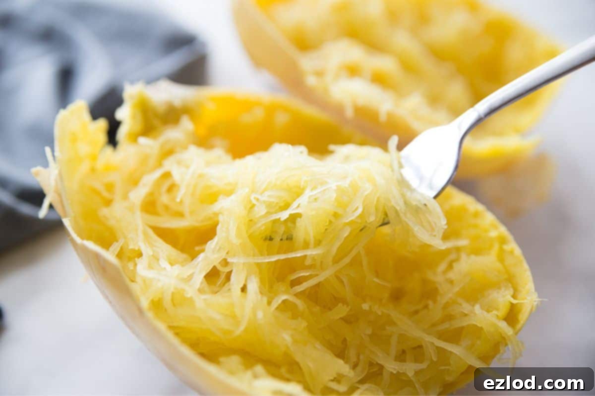 Low-Carb Spaghetti Squash Lasagna 4 A fork full of cooked spaghetti squash noodles inside of a squash boat.