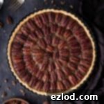 Plant-Based Sweet Bliss 7 Vegan pecan pie on a wooden backdrop with a bowl of pecans, forks and a brown cloth.