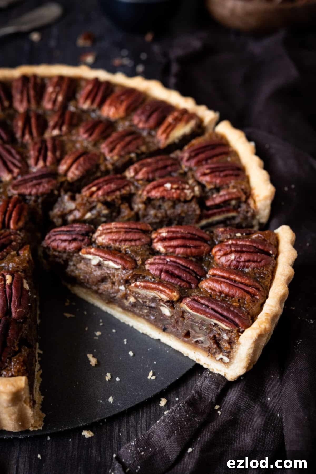 Pecan pie cut into slices on a wooden background with a brown cloth.