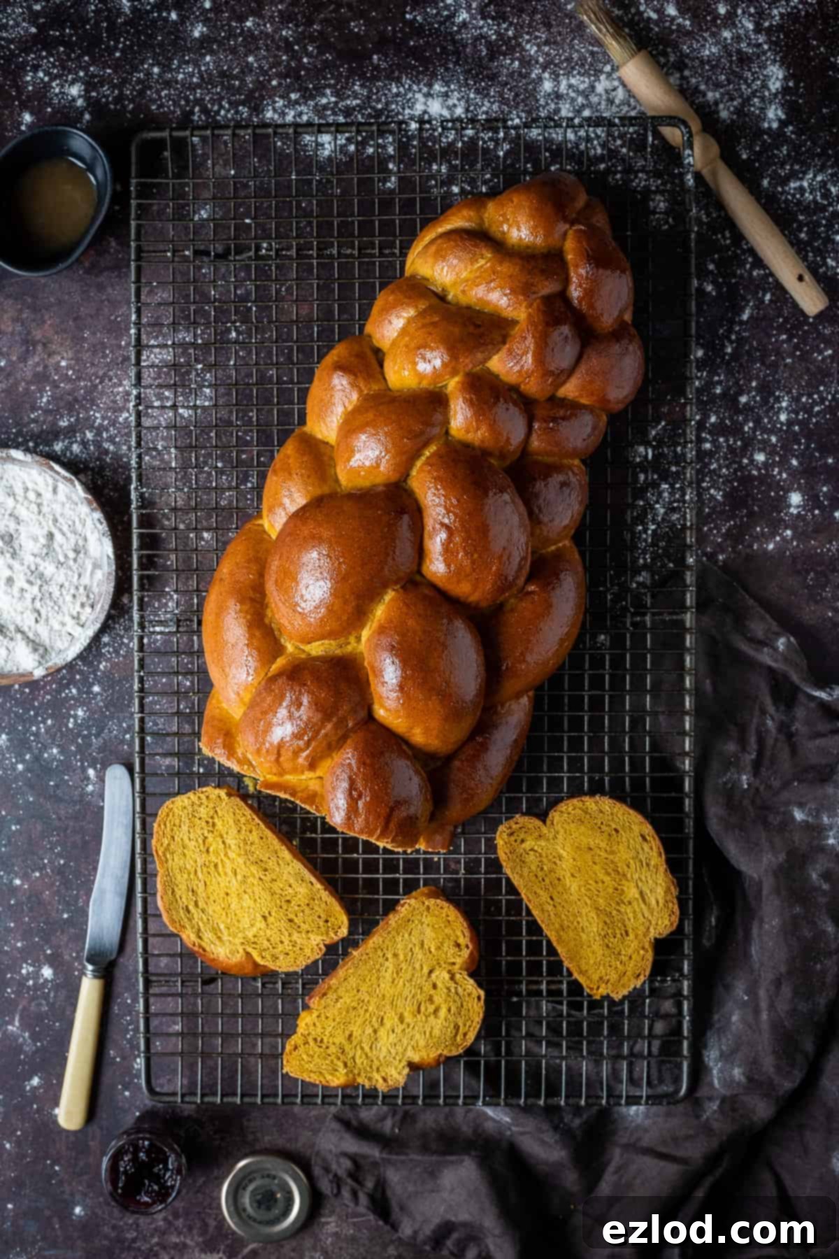 Vegan pumpkin challah bread on a wire rack on a dark background.
