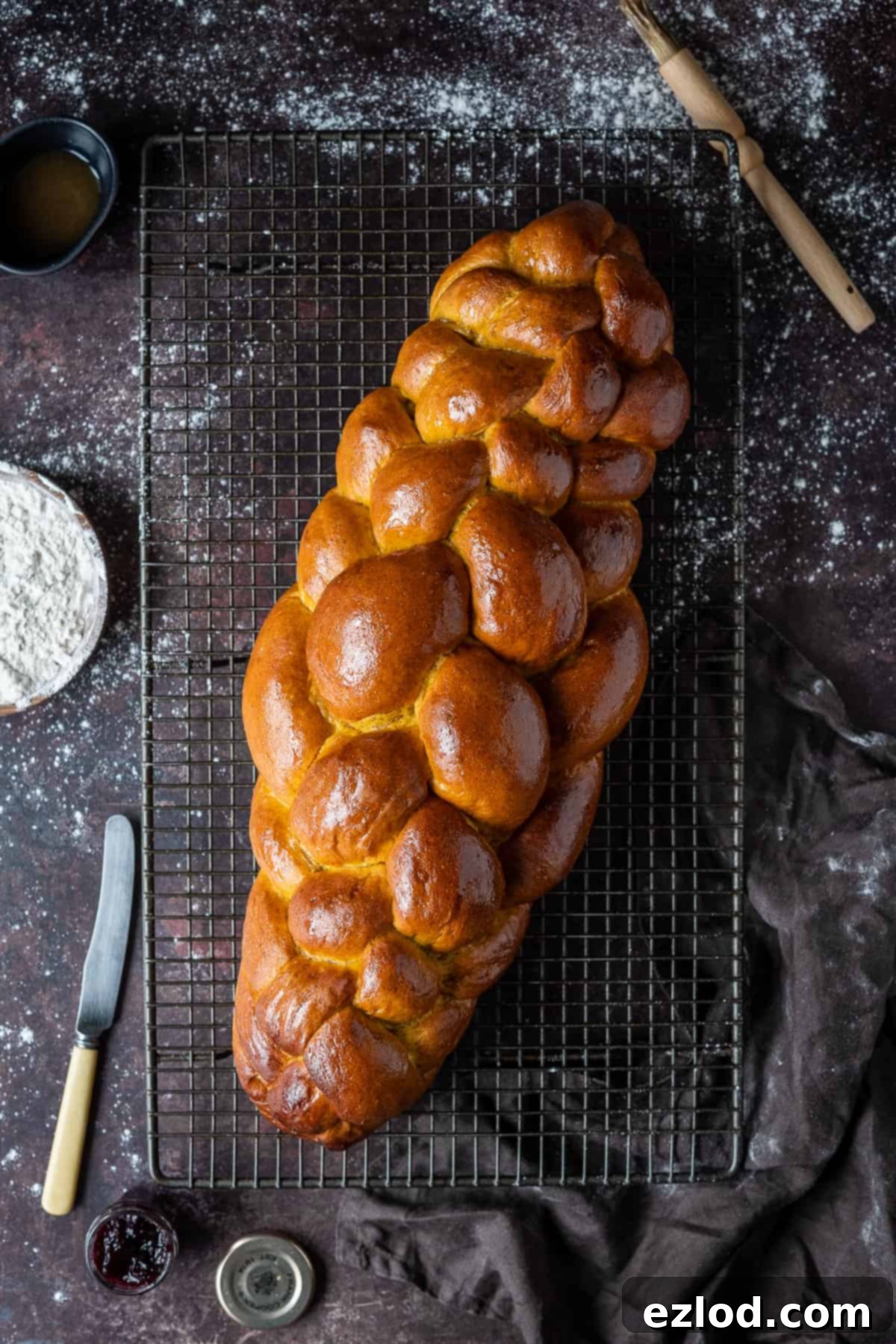 Baked vegan pumpkin challah loaf on a wire rack.