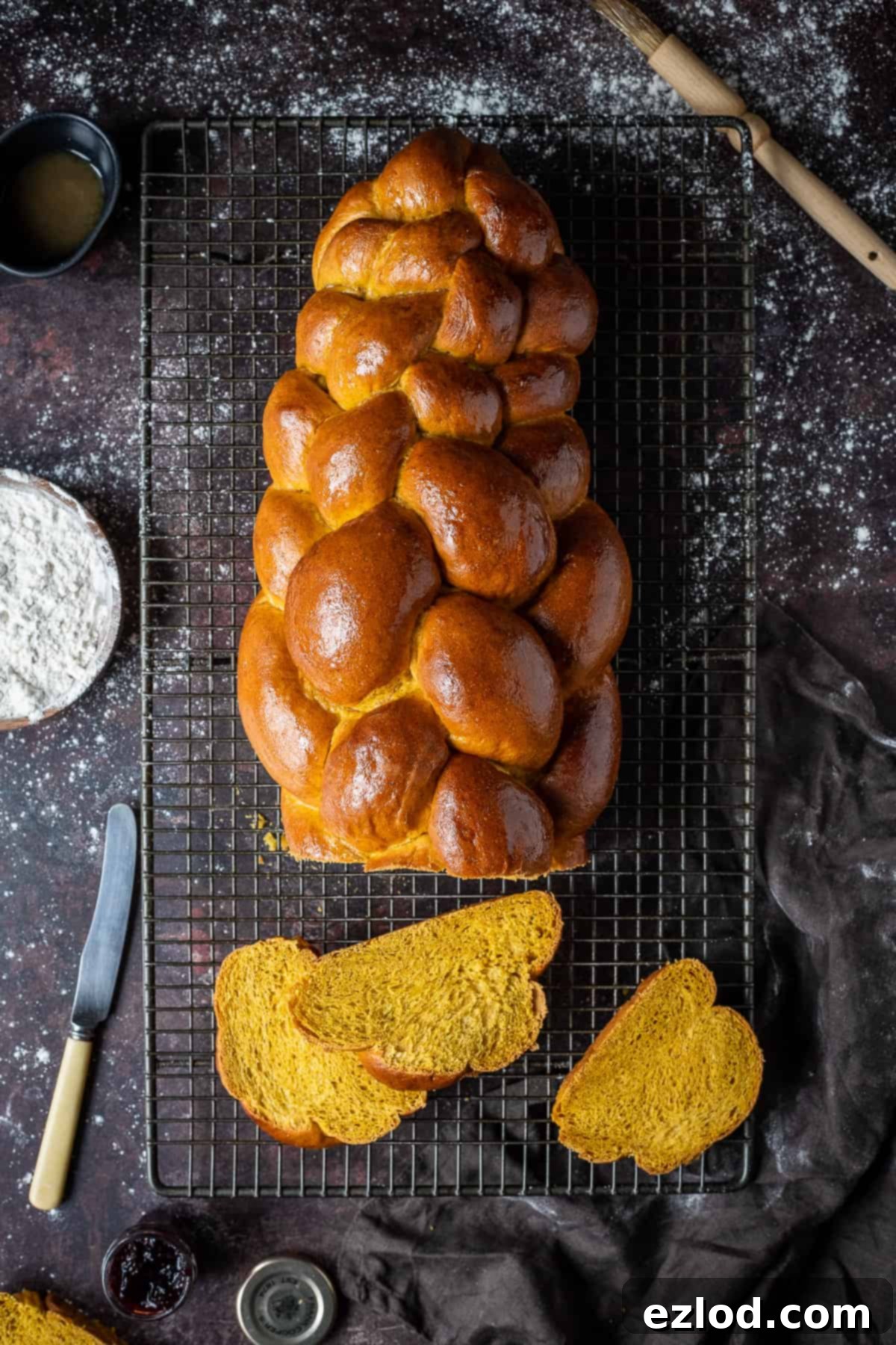 Sliced vegan pumpkin challah on a black wire rack on a dark background.