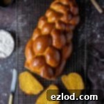 Vegan pumpkin challah bread on a wire rack on a dark background.