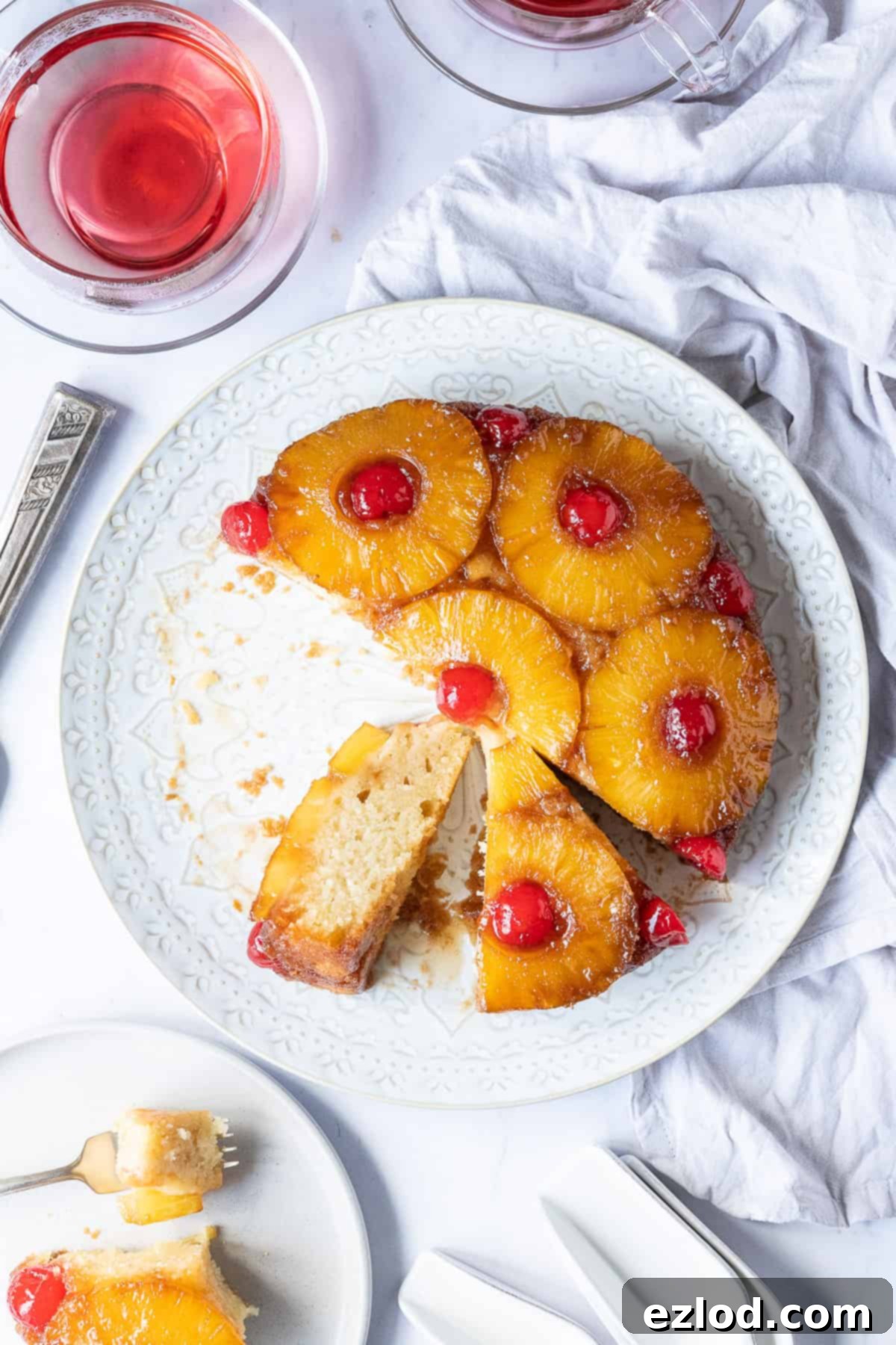 Vegan pineapple upside-down cake sliced on a white plate, resting on a marble background, highlighting its inviting texture and presentation.