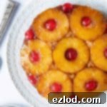 Close up of pineapple upside-down cake on a white plate.